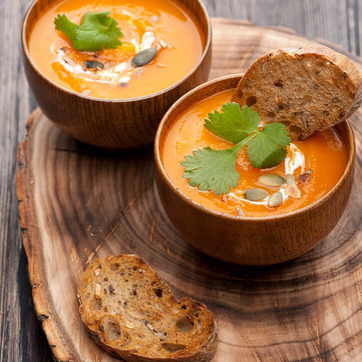 Kürbissuppe mit Brot auf Holzscheibe